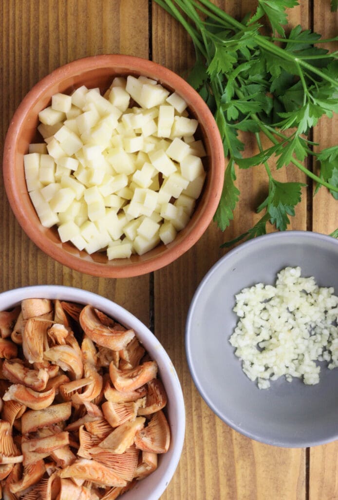 preparing ingredients for tart filling - pieces of cheese, cleaned, chopped saffron milk caps and crushed garlic